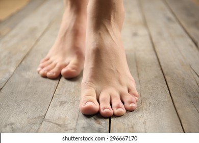 Weibliche Füße auf Holzhintergrund