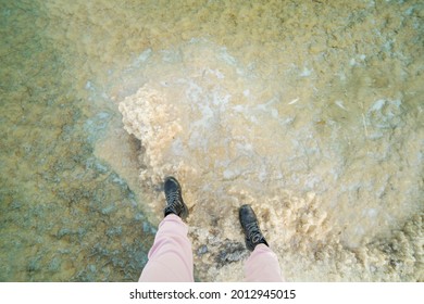 female feet in rough boots on salt in the dead sea top view. wide angle view. 