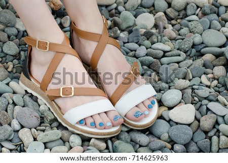 Female feet in sandals, pebbles, close-up