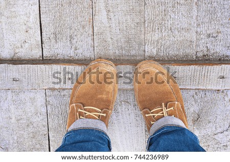 Female feet in shoes on wooden pavement.