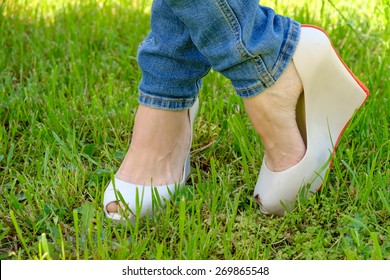 Female Feet In Shoes With Wedge Heels On Green Grass