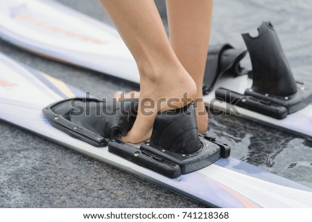 female feet slipping into water skis