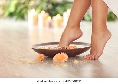 Female feet in spa wooden bowl on blurred background