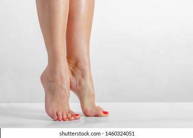 Female Feet, Feet Stand On The Fingers On A White Background, Smooth Skin, Foot Care. Barefoot. Clean And Soft Skin Of A Woman's Legs. Body Care Concept.