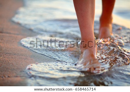 Female feet step on the sea wave. Summer vacations concept