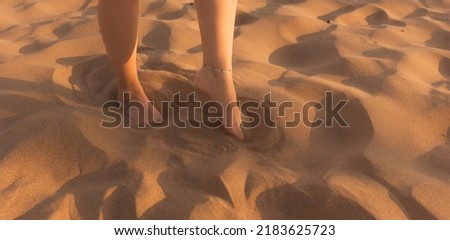 female feet walking in the desert sand, patterns in the sand