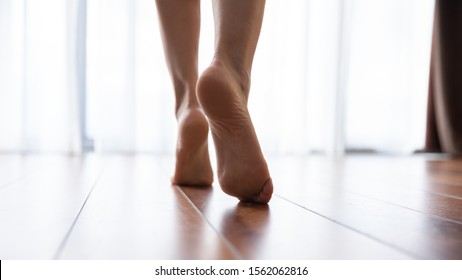 Female Feet Walking On Warm Heated Floor Close Up View, Barefoot Girl Legs Going On Hardwood Living Room Wooden Flooring At Modern Home House, Domestic Underfloor Heating Concept, Close Up Rear View