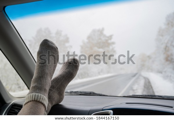 Female feet in woolen socks on the
dashboard of a car in winter. Windshield
view