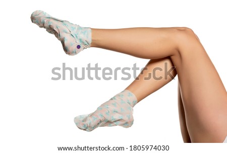 Female feet wrapped with plastic bag with foot mask