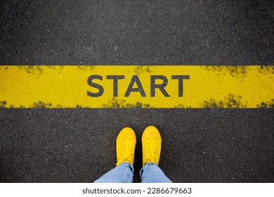 Female feet in yellow sneakers standing on street background with word new start written. Yellow race line beginning idea concept. Top view. Businessman of starting - Powered by Shutterstock