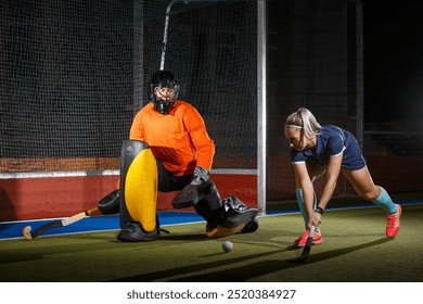 Female field hockey player attacking the goalie to score a goal. - Powered by Shutterstock