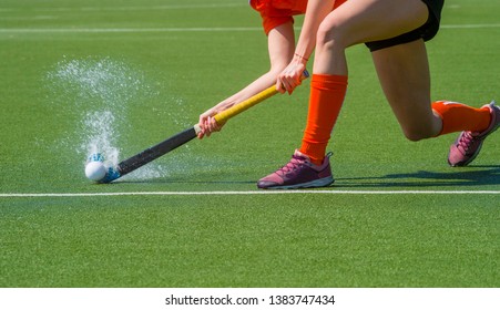 Female field hockey player passing to a team mate on a modern, water artificial astroturf field - Powered by Shutterstock