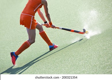 Female field hockey player passing to a team mate on a modern, water artificial astroturf field