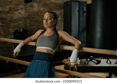 Female fighter with bandaged hands standing leaned at wooden bar - Powered by Shutterstock