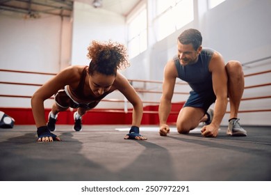 Female fighter doing push-ups while having sports training with instructor in health club.  - Powered by Shutterstock