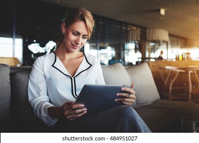 Female Financier Is Reading Financial News In Internet Via Touch Pad During Work Break In Modern Cafe. Confident Woman Lawyer Is Using Digital Table, While Is Waiting Client In An Informal Setting