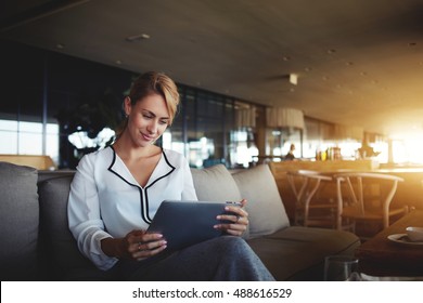 Female financier is reading financial news in internet via touch pad during work break in modern cafe. Confident woman lawyer is using digital table, while is waiting client in an informal setting - Powered by Shutterstock