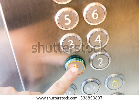 Female finger presses the button on the first floor in an elevator