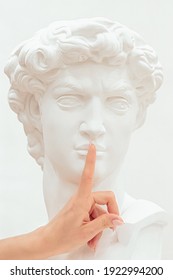 Female fingers touch the lips of the sculpture of a man, showing a gesture of silence.Creative concept. - Shutterstock ID 1922994200
