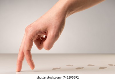 Female fingers walking on white surface with footsteps behind it