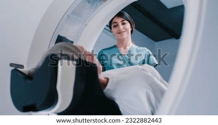 Female finished magnetic resonance imaging, Patient is moving out of MRI scanner capsule. Female doctor asks patient about well-being after examining. Doctor is smiling and have talk with woman.