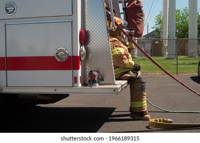 Female Fire Fighter Taking A Needed Break On The Back Of Engine Drinking Water From Working Training 