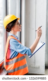 Female Firefighter In Helmet And Uniform Holding Clipboard And Pen In Hands