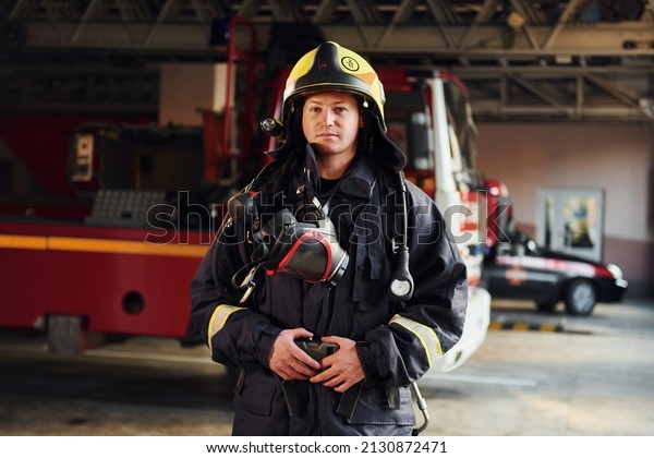 Female firefighter in protective uniform standing\
near truck.