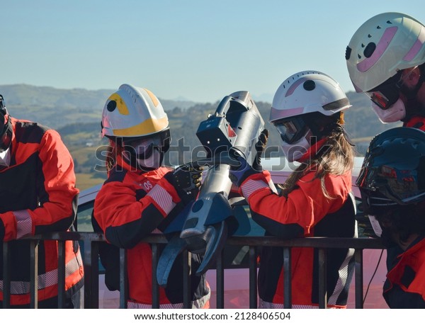 Female firefighters holding a jaws of life, a\
tool for emergencies
