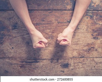 Female fists clenched on a wooden table in anger - Shutterstock ID 272600855