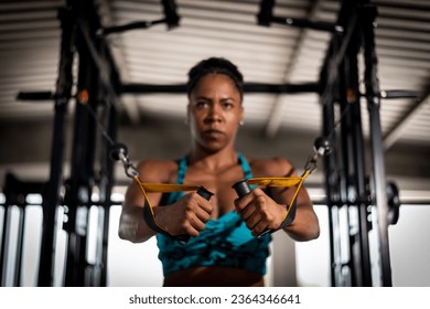 A female fitness enthusiast using a resistance training device while holding a pair of scissors in her hands at the gym - Shutterstock ID 2364346641