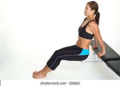 A female fitness instructor demonstrates the starting position of tricep bench dips
