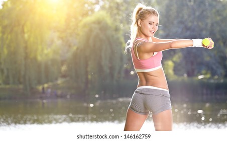  female fitness instructor exercising with small weights in green park  - Powered by Shutterstock