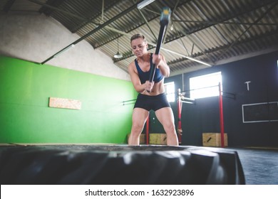 Female Fitness Model Doing   Exercise In A Gym With A Sledge Hammer