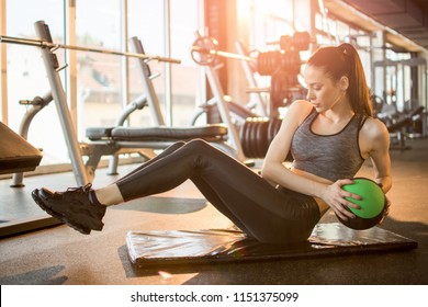 Female Fitness Model Exercising With Medicine Ball At Gym.