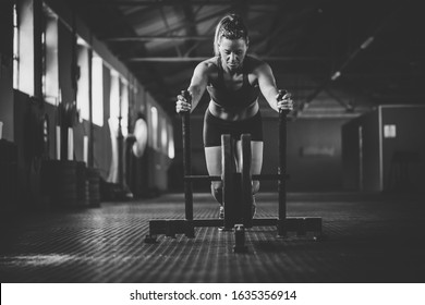 Female fitness model pushing a sled in a gym. - Shutterstock ID 1635356914