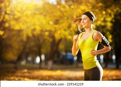 Female fitness model training outside on a warm fall day and listening to music. Sport lifestyle. - Powered by Shutterstock