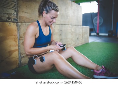 Female fitness model using electronic muscle stimulation technology after a hard training session.