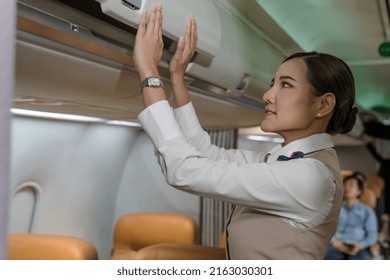 Female Flight Attendant Closing Overhead Compartment Preparing For Plane Boarding, Asian Cabin Crew Woman Checking Compartment Before Plane Taking Off, Asian Airhostess Woman Working On Plane