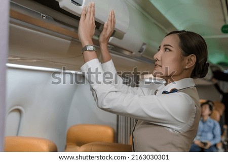 Female flight attendant closing overhead compartment preparing for plane boarding, Asian cabin crew woman checking compartment before plane taking off, Asian Airhostess woman working on plane