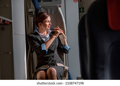 Female Flight Attendant Fastening Seatbelt In Airplane