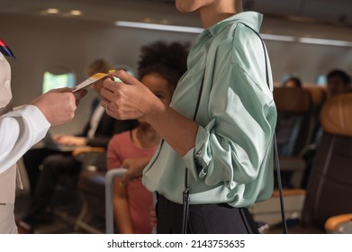 Female Flight Attendant In Suit Uniform Standing At Airplane Entrance And Checking Woman Passenger Boarding Pass For Flight Information