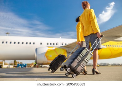 Female flight attendants with travel bags walking down airfield - Shutterstock ID 2095985383