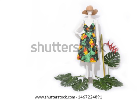 Female in floral .palm pattern sundress,hat  on full mannequin isolated with monstera and bird of paradise


