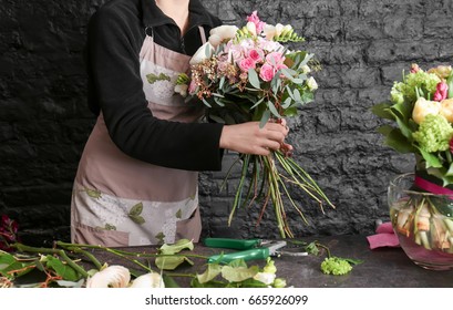 Female Florist Creating Beautiful Bouquet In Flower Shop On Black Brick Wall Background