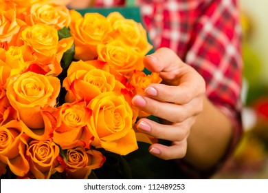 Female florist in flower shop or nursery presenting roses, close-up - Powered by Shutterstock