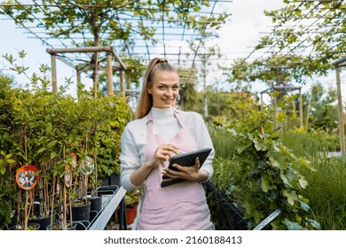 Female Florist Holding Tablet. Owner Of Garden Centre Standing A Smiling At Camera.