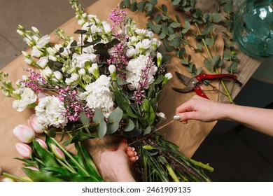 female florist makes a bouquet in a flower shop, spring bouquet - Powered by Shutterstock