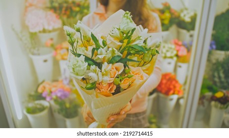 Female Florist Makes Flower Bunch, She Cuts Off Wrapping Paper Working In Flower Shop. Cute Young Caucasian Professional Makes Bouquet For Sale In Floral Store. Floristry Handmade Small Business