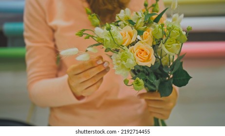 Female Florist Makes Flower Bunch, She Cuts Off Wrapping Paper Working In Flower Shop. Cute Young Caucasian Professional Makes Bouquet For Sale In Floral Store. Floristry Handmade Small Business